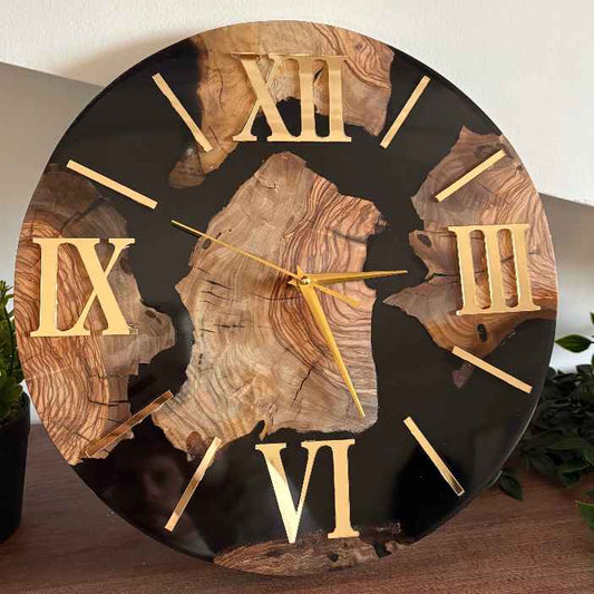 Primo piano di un lussuoso orologio da parete artigianale creato su misura a Roma, che combina il calore della radica di ulivo naturale con un'elegante base in resina epossidica nera lucida e luminosi numeri romani dorati.