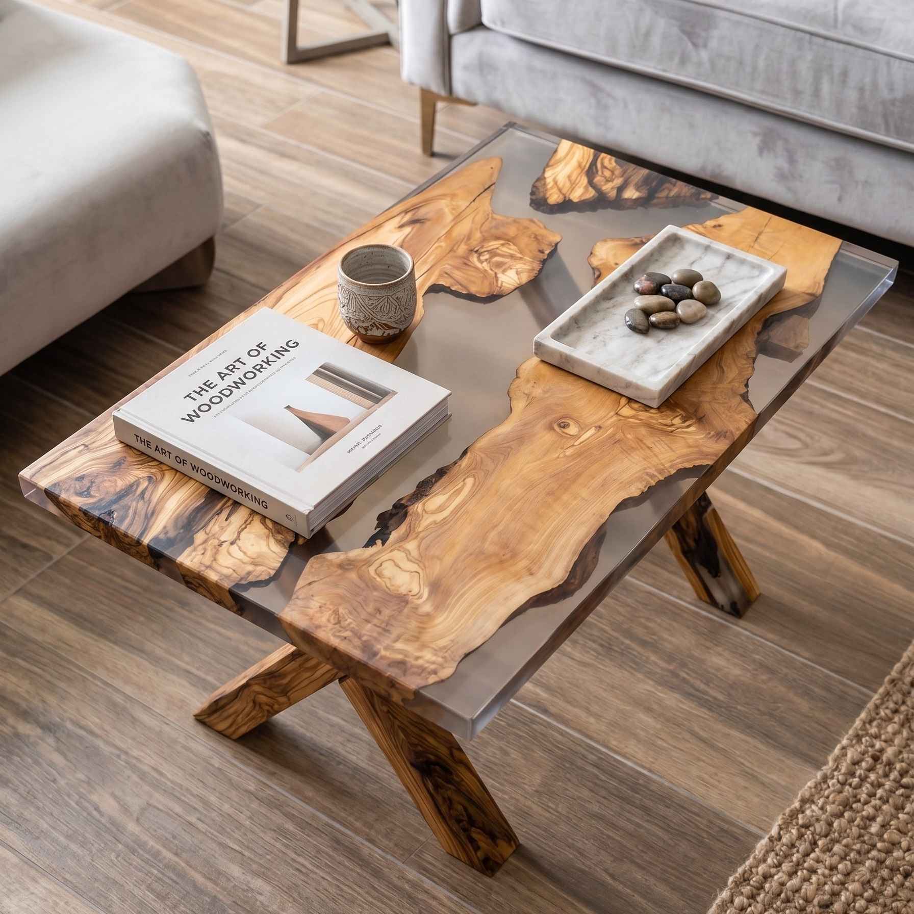 Tavolino da salotto di design realizzato in legno di ulivo e resina trasparente, arredato con un libro e un vassoio decorativo, ambientato in un soggiorno elegante. Realizzato su misura a Roma da Marco morrone Wood and Resin Design