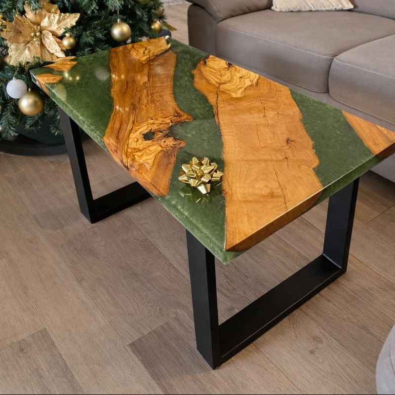 Tavolino da salotto artigianale in legno di ulivo e resina epossidica verde, stile river table, con gambe nere in metallo, ambientato in un soggiorno accanto a un albero di Natale.