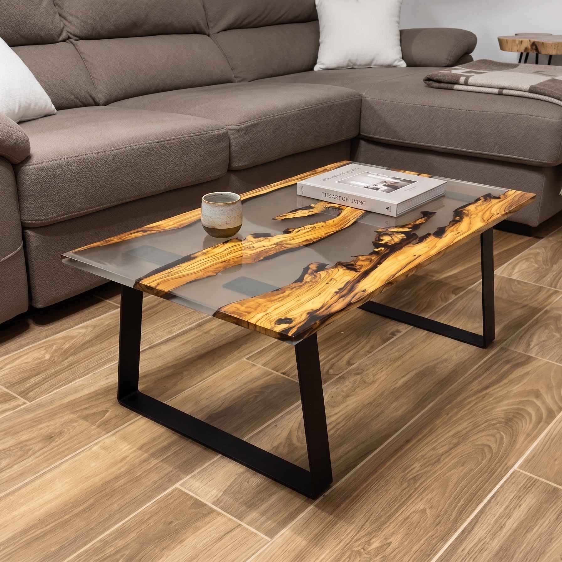 Tavolino da salotto artigianale in legno di ulivo e resina trasparente, con gambe in metallo nero, ambientato in un soggiorno.